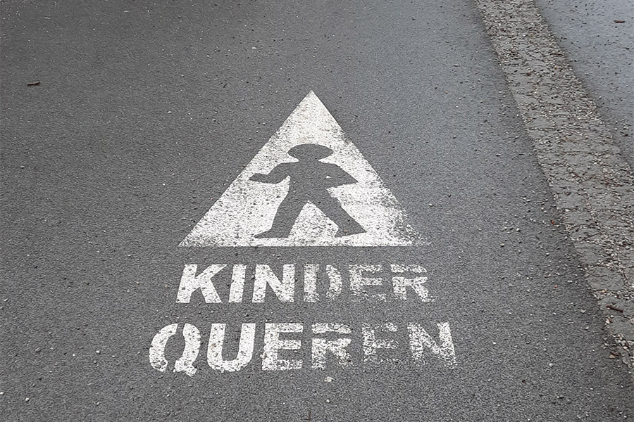 Straßenmarkierung mit folgender Warnung: Kinder queren